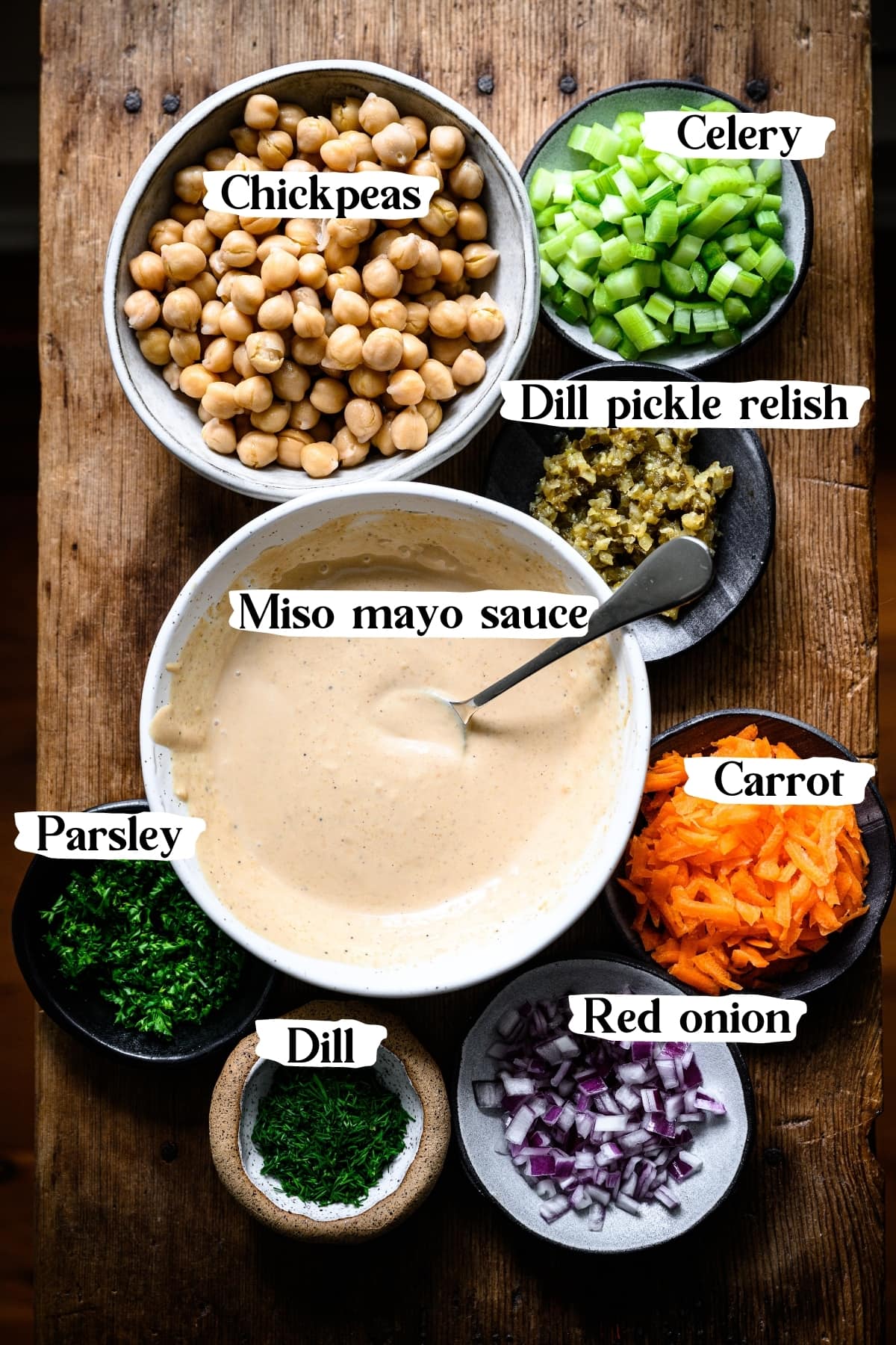 overhead view of ingredients for vegan tuna salad, including chickpeas, carrot, celery, onion, dill, parsley and miso mayo sauce.