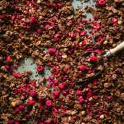 overhead view of chocolate hazelnut granola with freeze-dried raspberries on sheet pan.