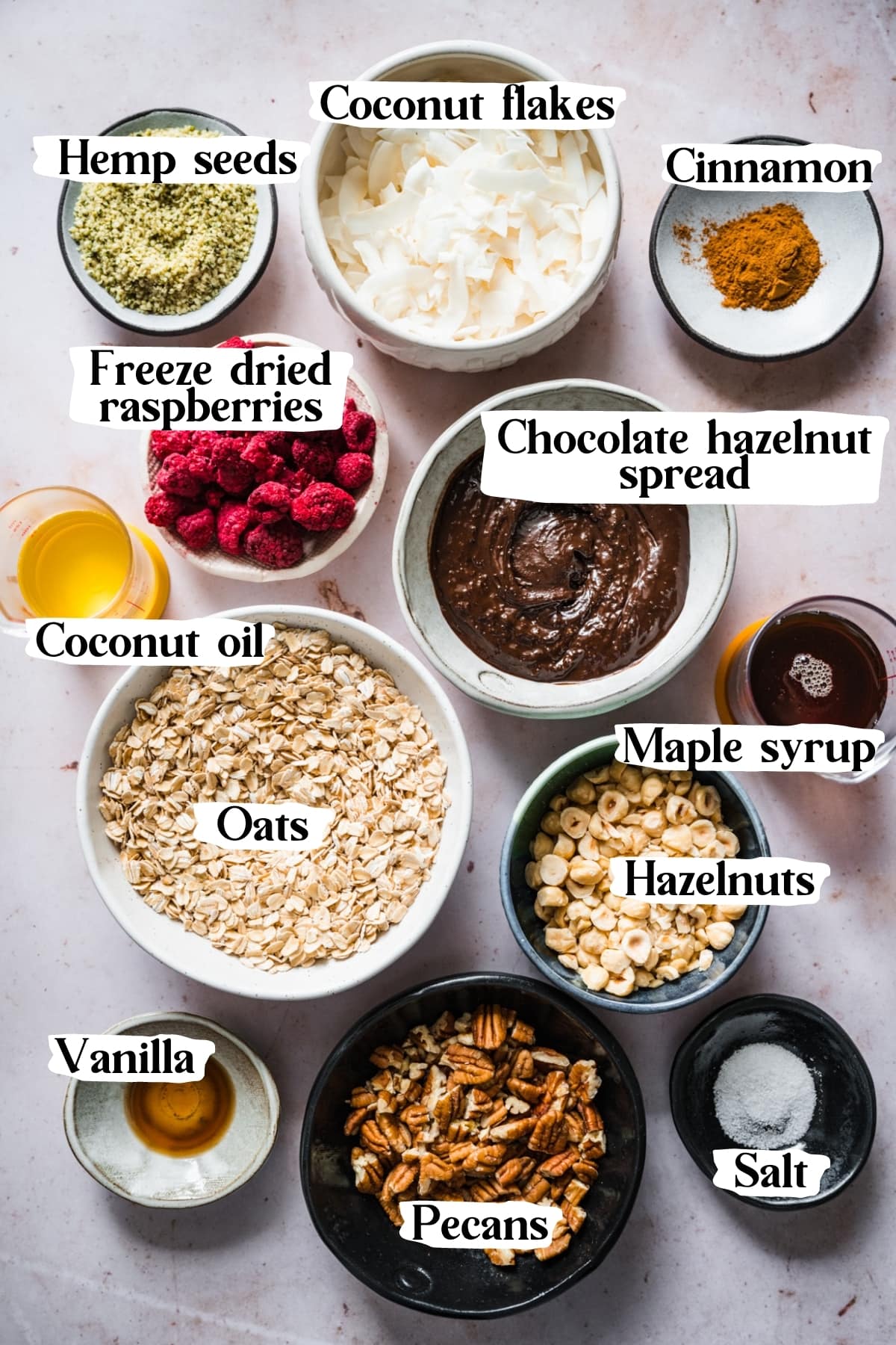 overhead view of ingredients for vegan chocolate hazelnut raspberry granola in small bowls. 