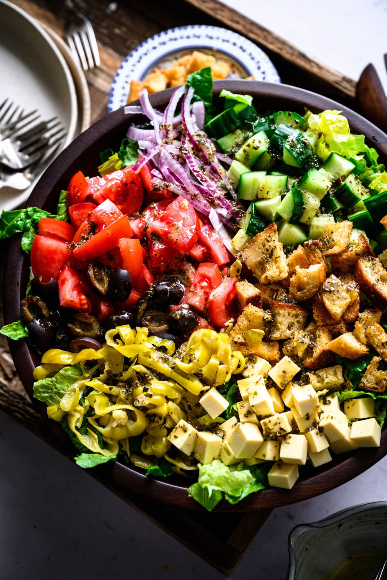 close up overhead view of vegan italian chopped salad in large wood salad bowl. 