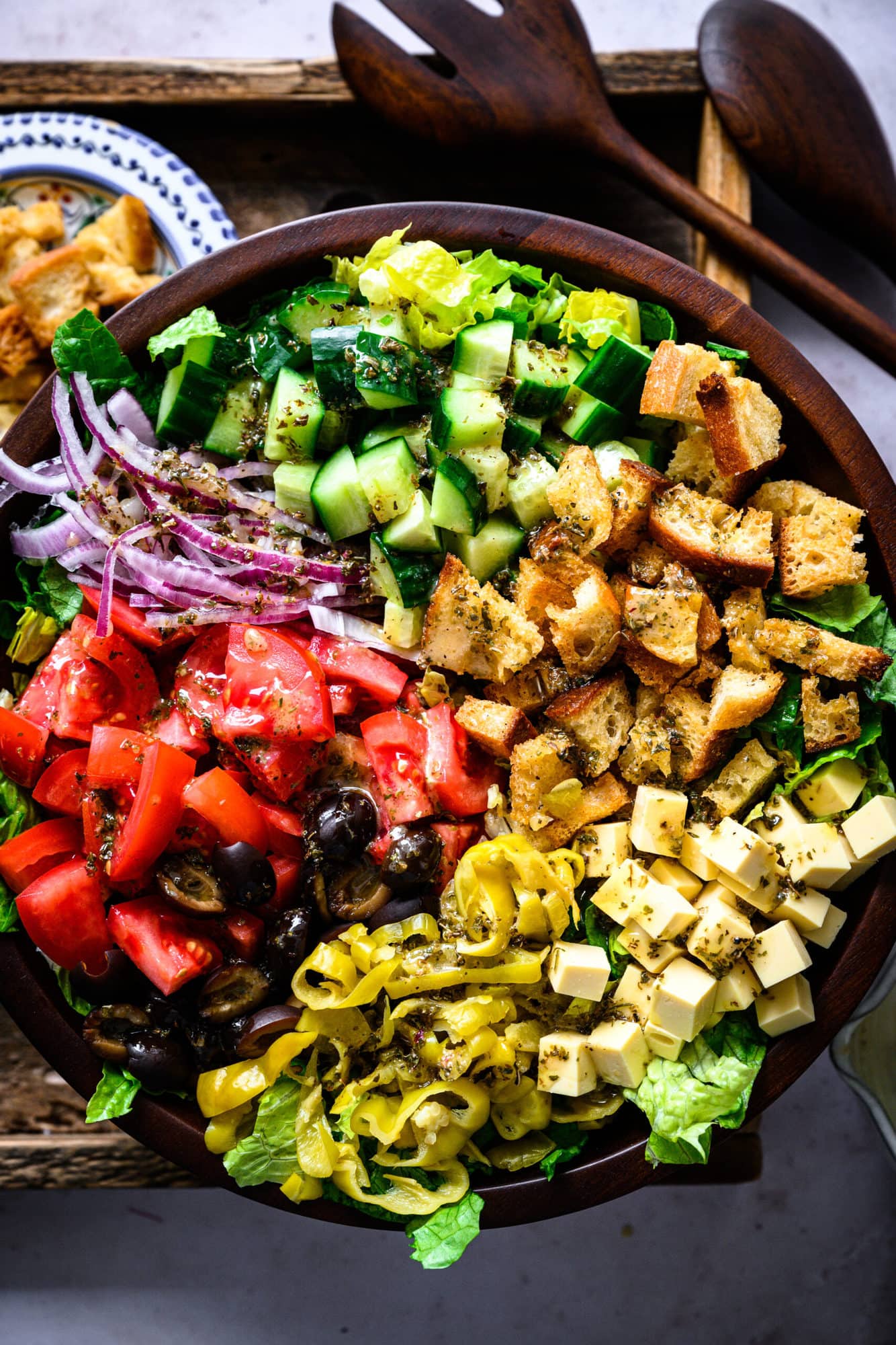 close up overhead view of vegan italian chopped salad in large wood salad bowl. 