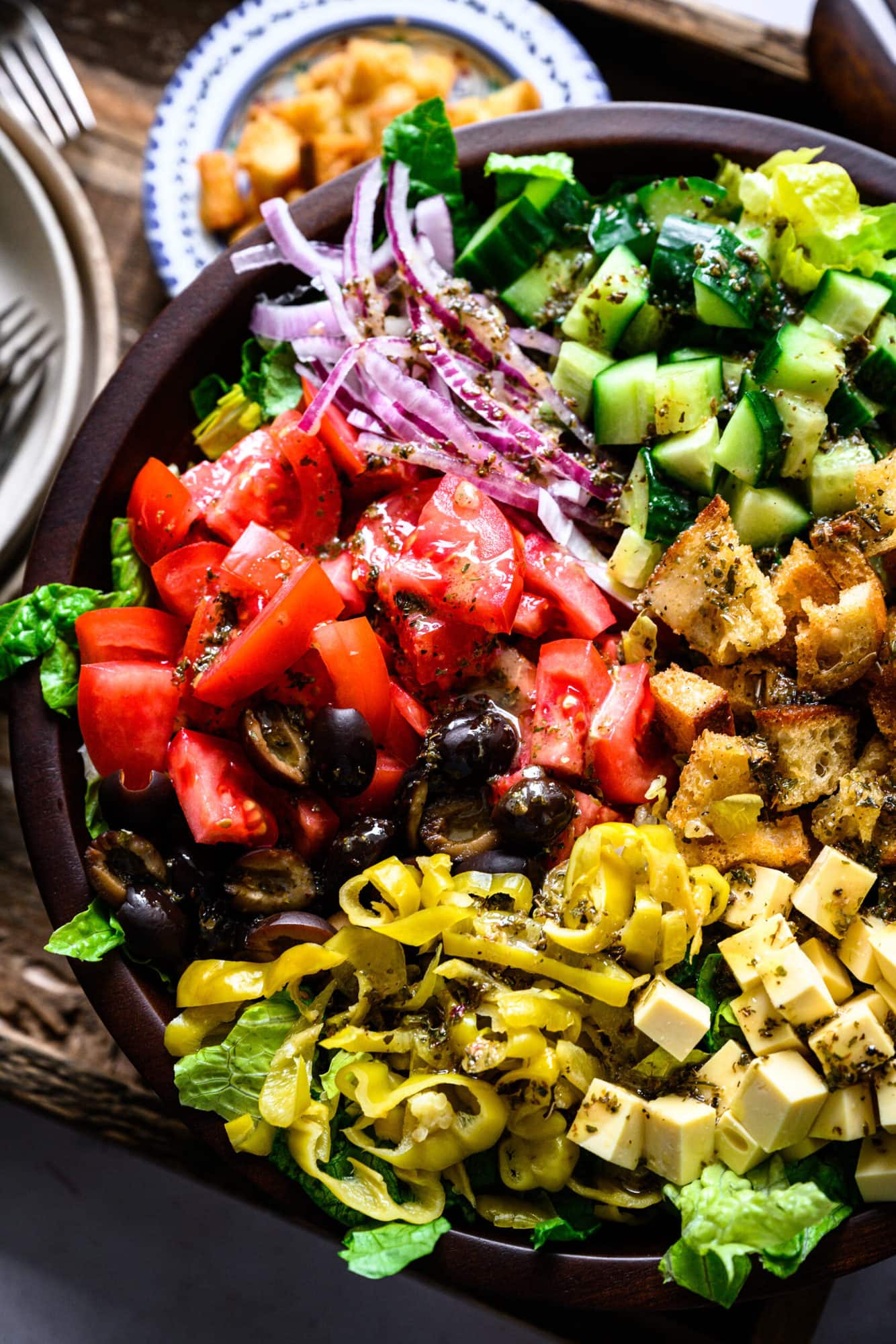 close up overhead view of vegan italian chopped salad in large wood salad bowl. 