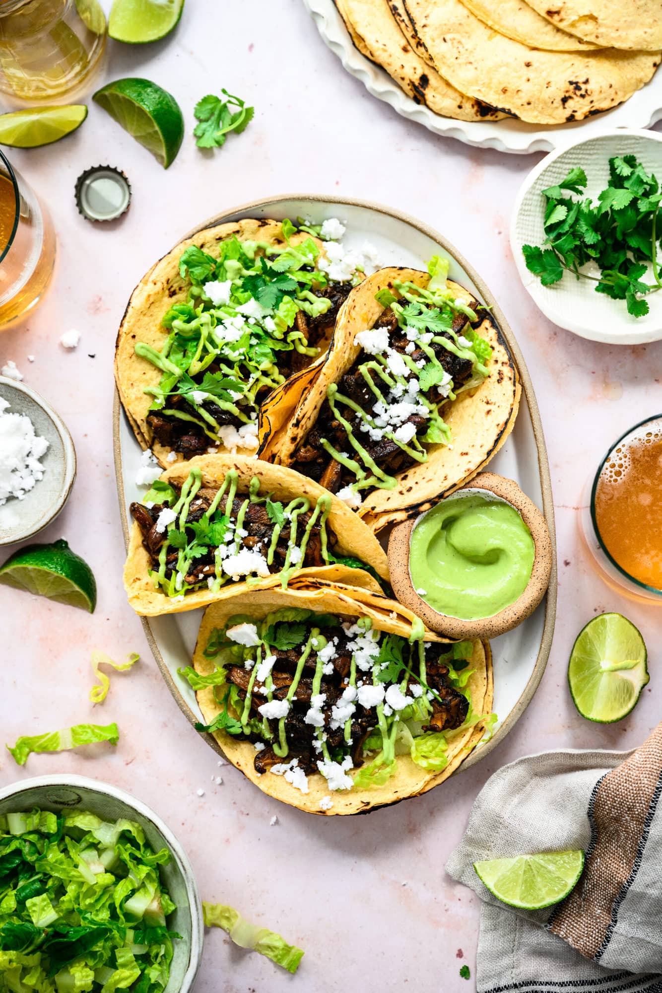overhead view of mushroom shawarma tacos on a platter with cilantro tahini sauce and feta.
