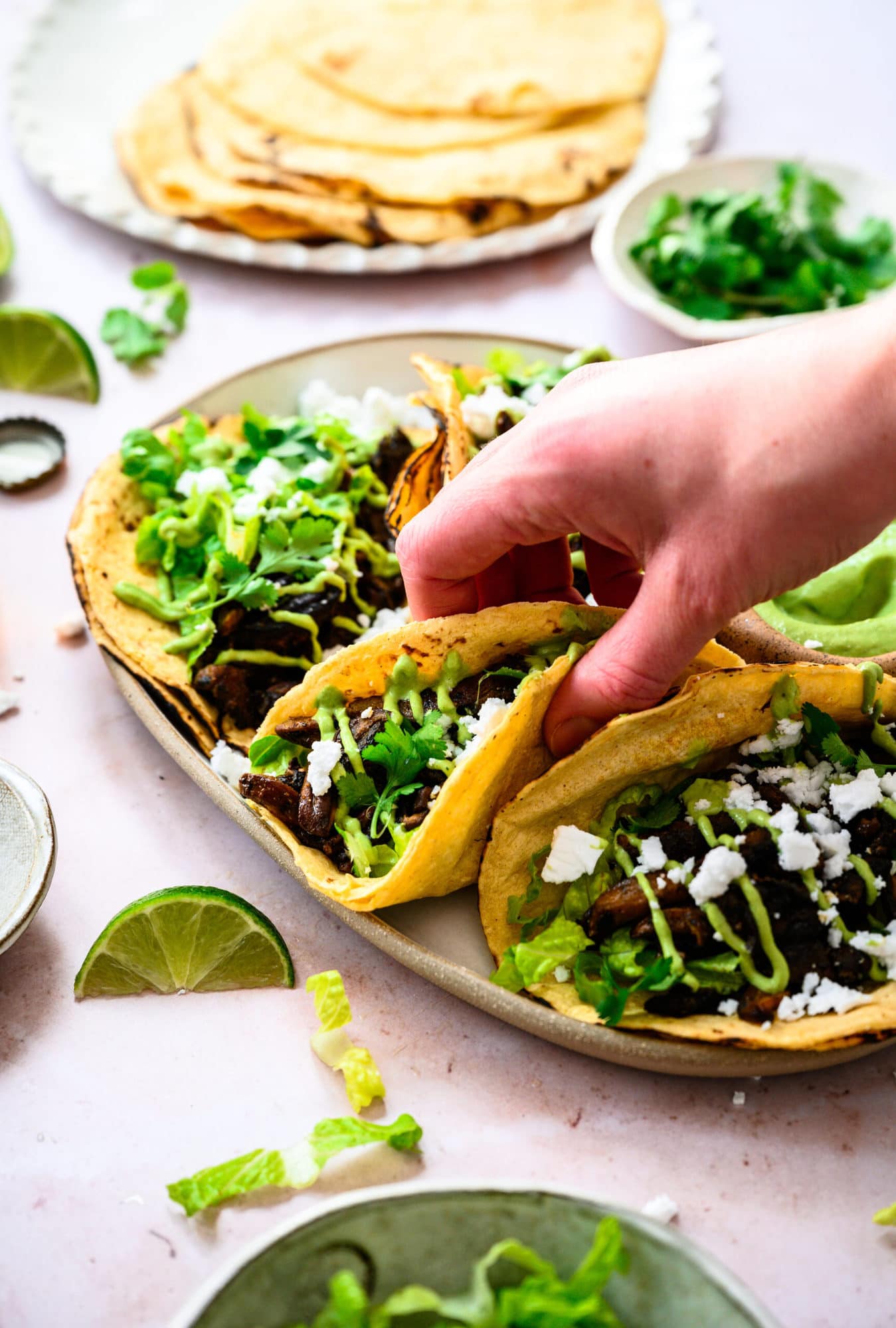 person grabbing mushroom shawarma taco off of platter.