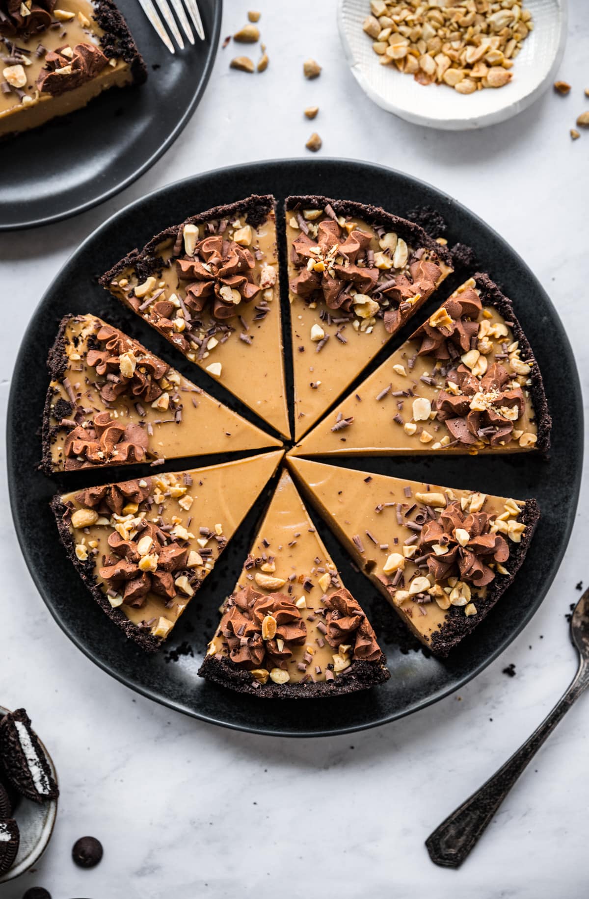 overhead view of peanut butter pie slices with chocolate cookie crust on black plate. 