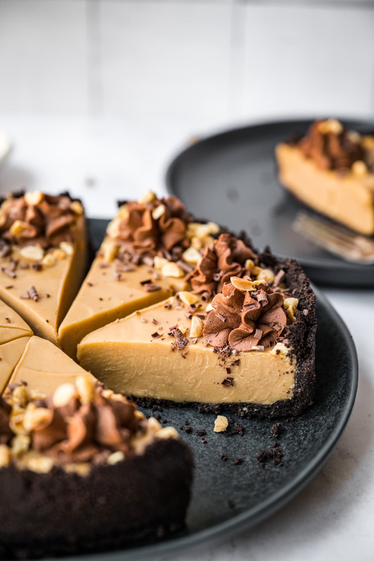 close up view of peanut butter pie with chocolate cookie crust on black plate. 