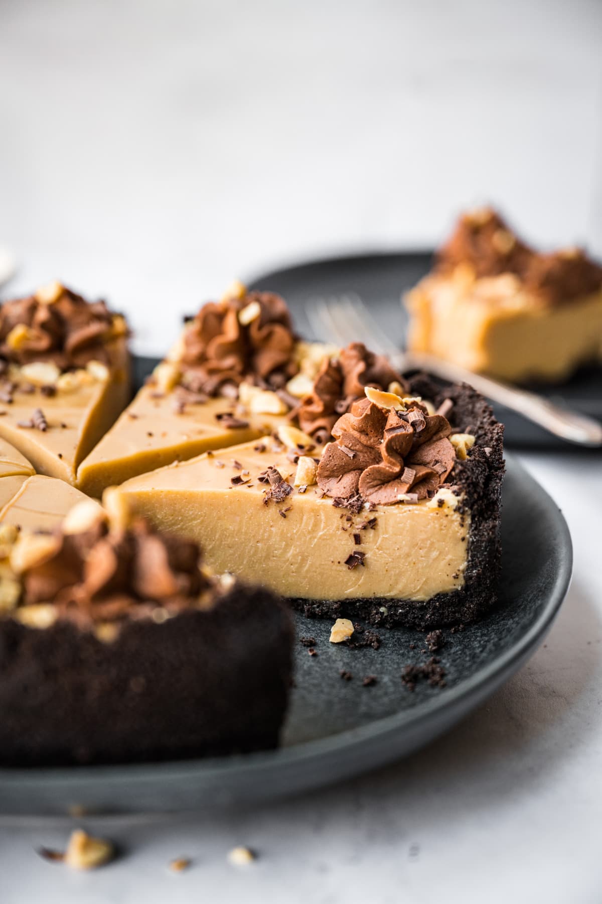 close up view of peanut butter pie with chocolate cookie crust on black plate. 