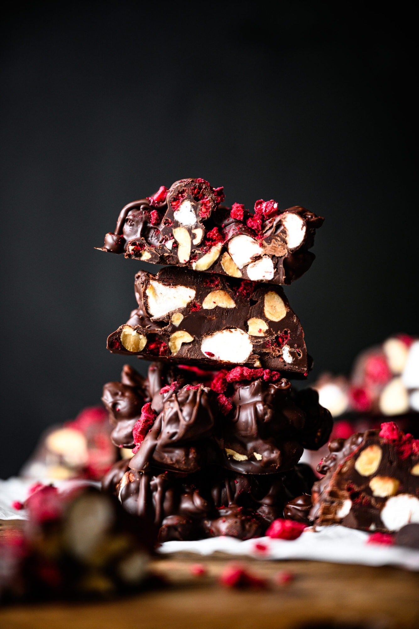 stack of dark chocolate peanut marshmallow clusters with freeze dried raspberries.