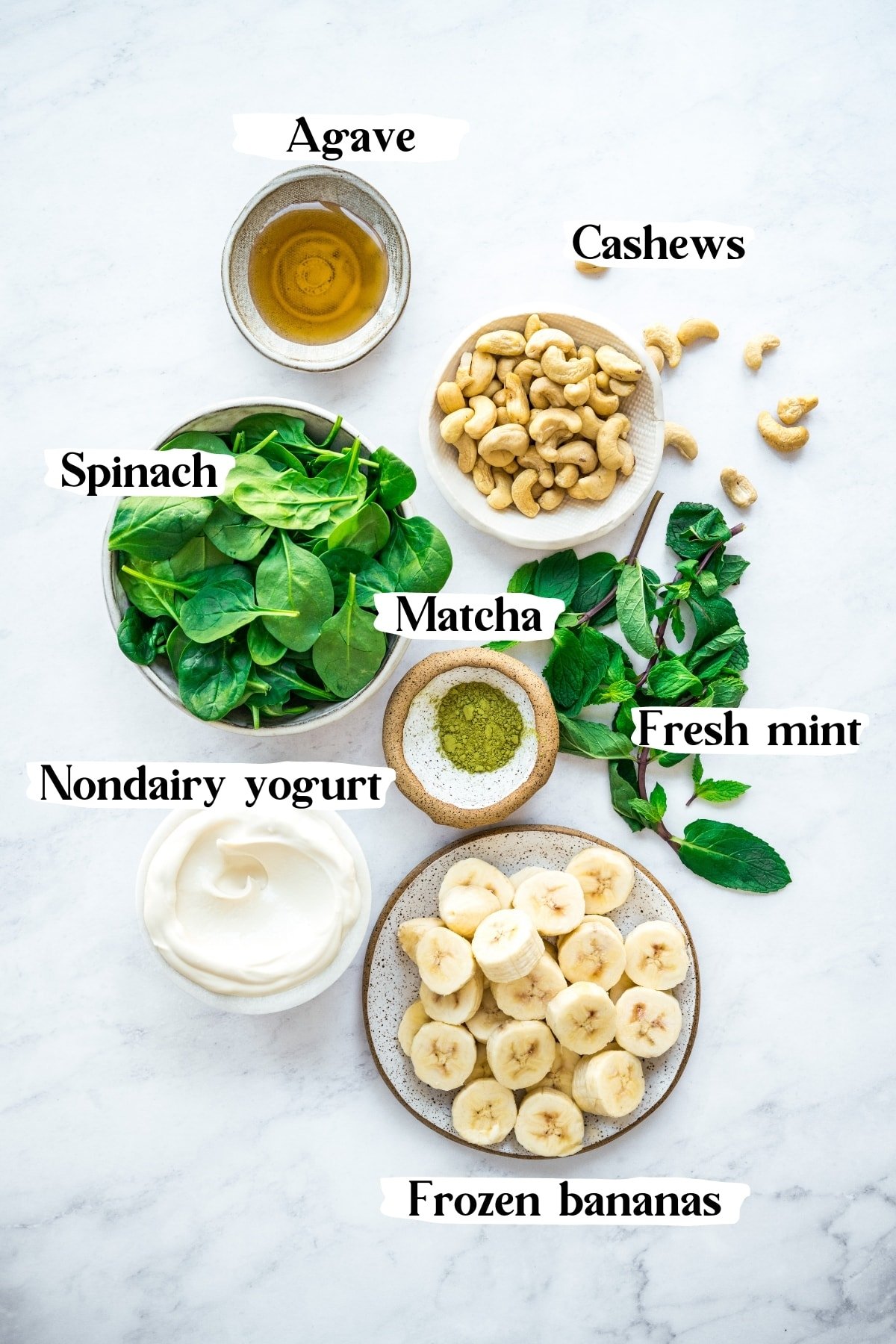 overhead view of ingredients for healthy shamrock shake, including frozen bananas, cashews, mint, spinach and yogurt. 
