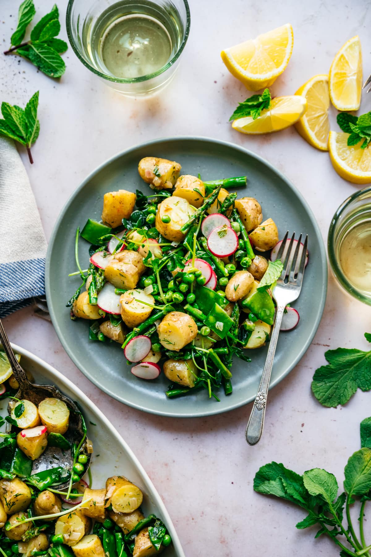 overhead view of asparagus potato salad with peas and radishes on a blue plate with fork.