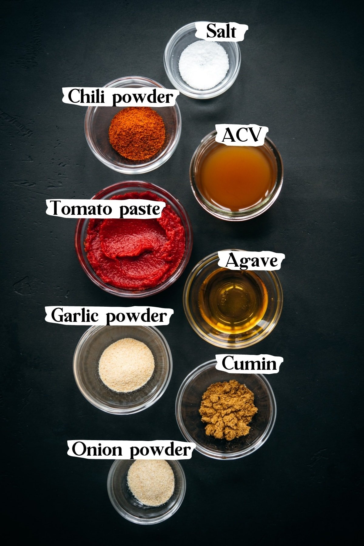 overhead view of ingredients and spices for homemade taco sauce in small glass bowls. 