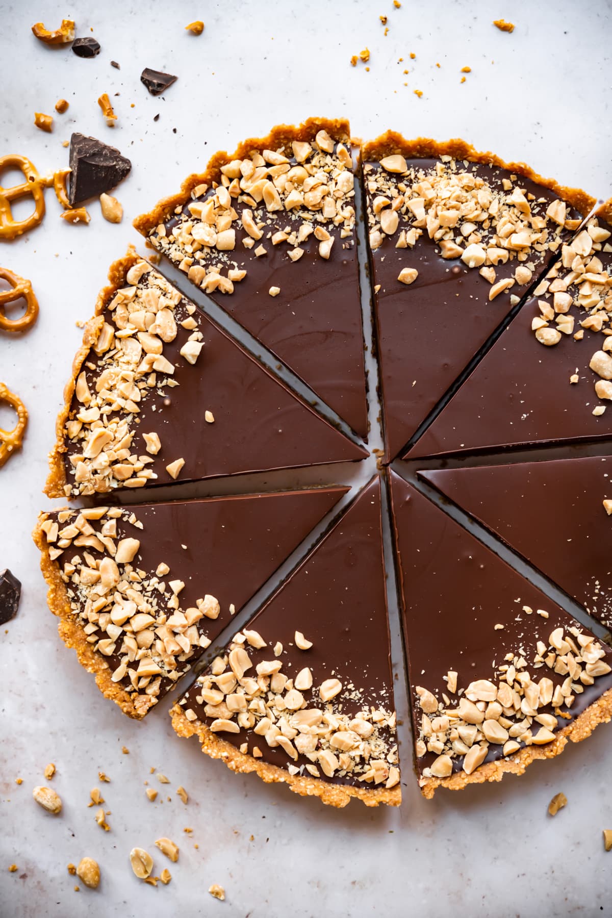 overhead view of chocolate peanut butter pretzel tart cut into slices. 