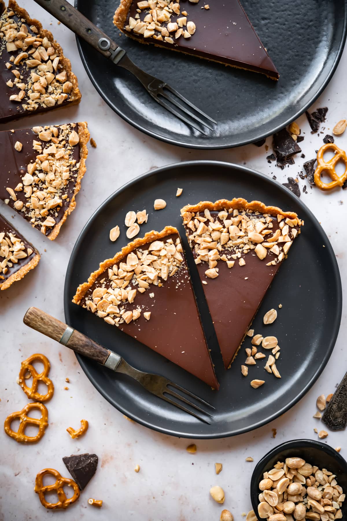 overhead view of 2 slices of chocolate peanut butter pretzel tart on a black plate. 