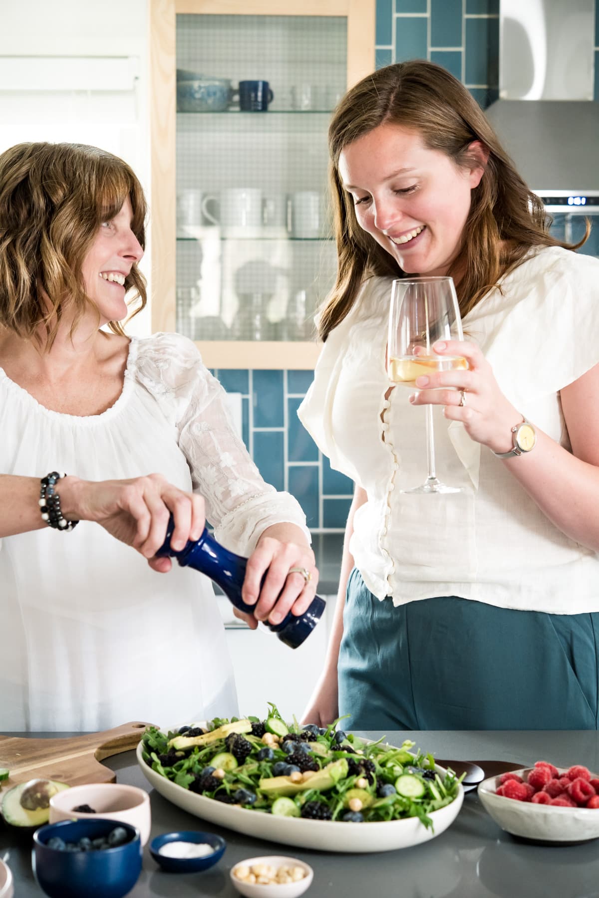 headshot of Lexi and Beth from Crowded Kitchen in the kitchen with wine. 