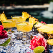 overhead view of pineapple mimosa on blue tile with pool in background.