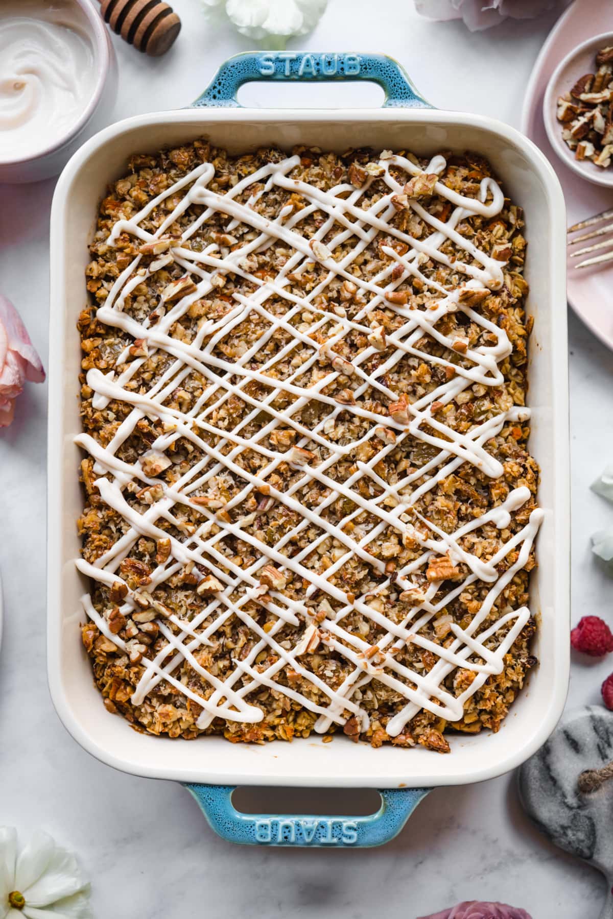 overhead view of vegan carrot cake baked in a blue baking dish with cream cheese glaze. 