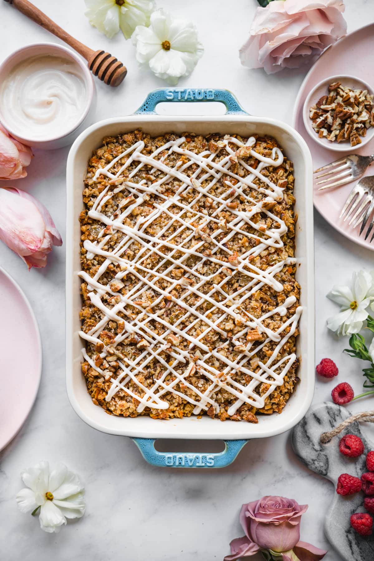 overhead view of vegan carrot cake baked in a blue baking dish with cream cheese glaze. 