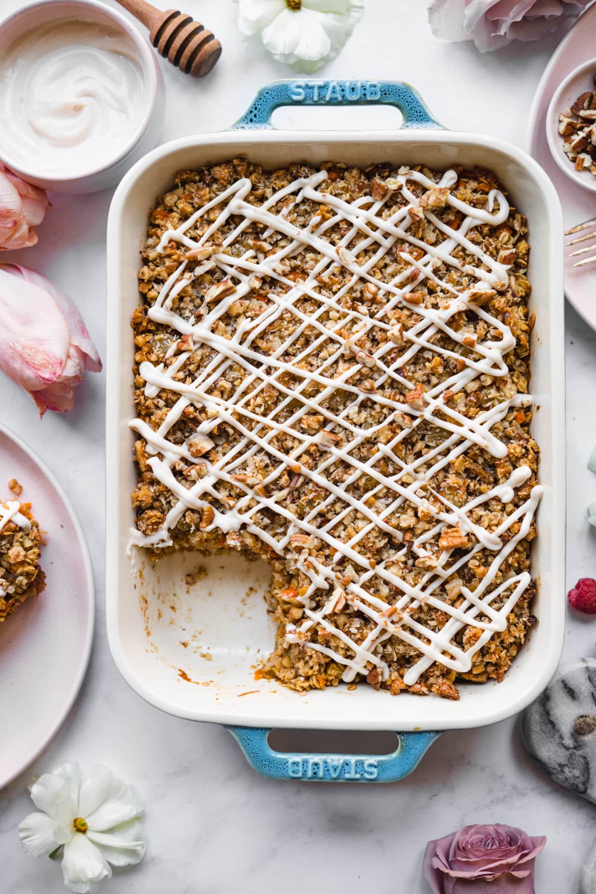 overhead view of vegan carrot cake baked in a blue baking dish with cream cheese glaze. 