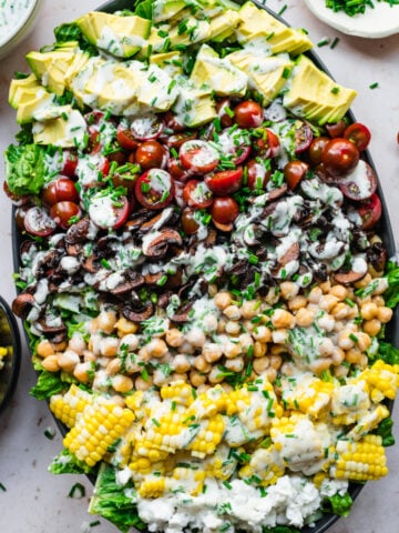 overhead view of vegan cobb salad on a platter topped with vegan ranch dressing.