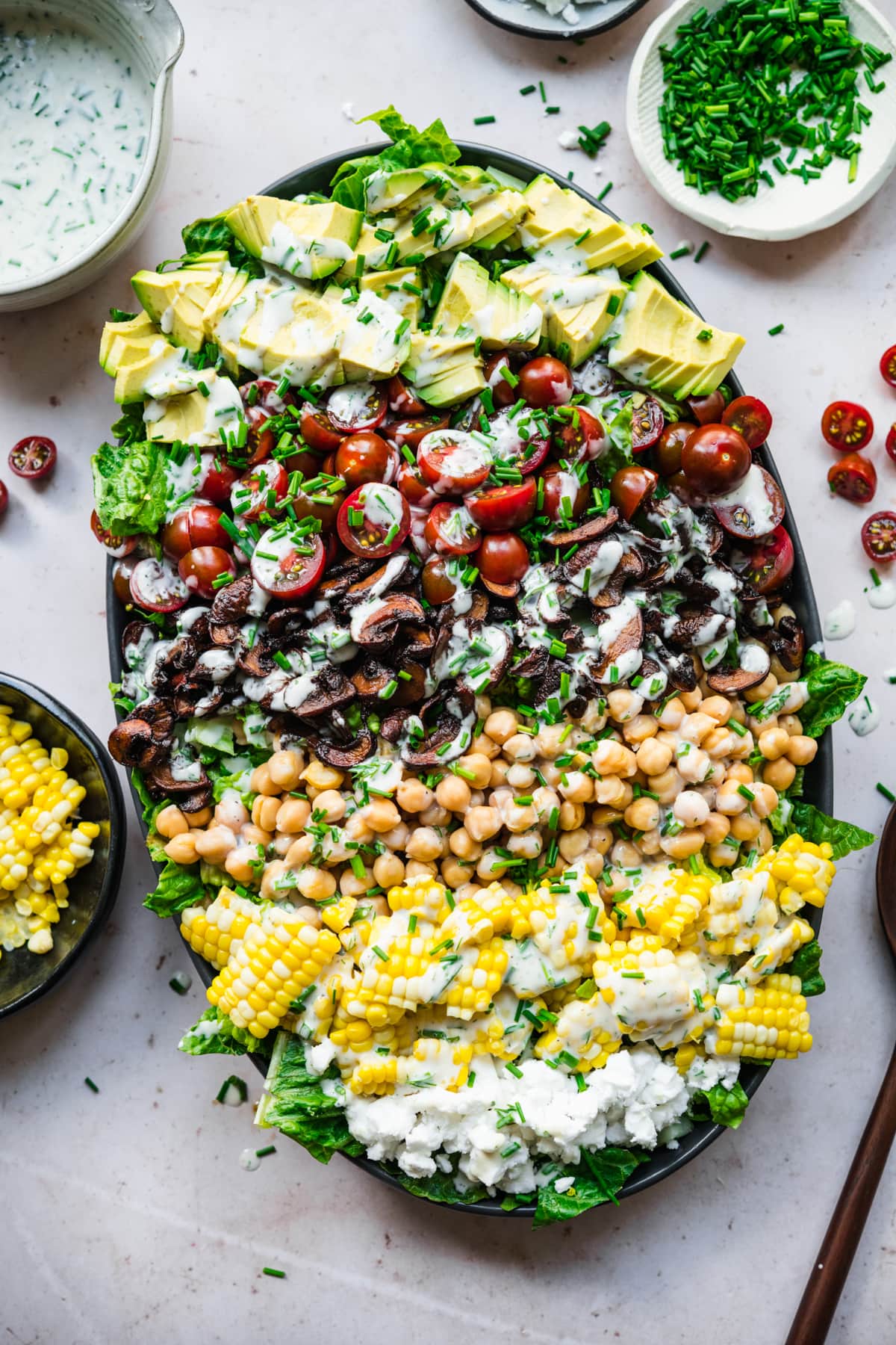 overhead view of vegan cobb salad on a platter topped with vegan ranch dressing. 