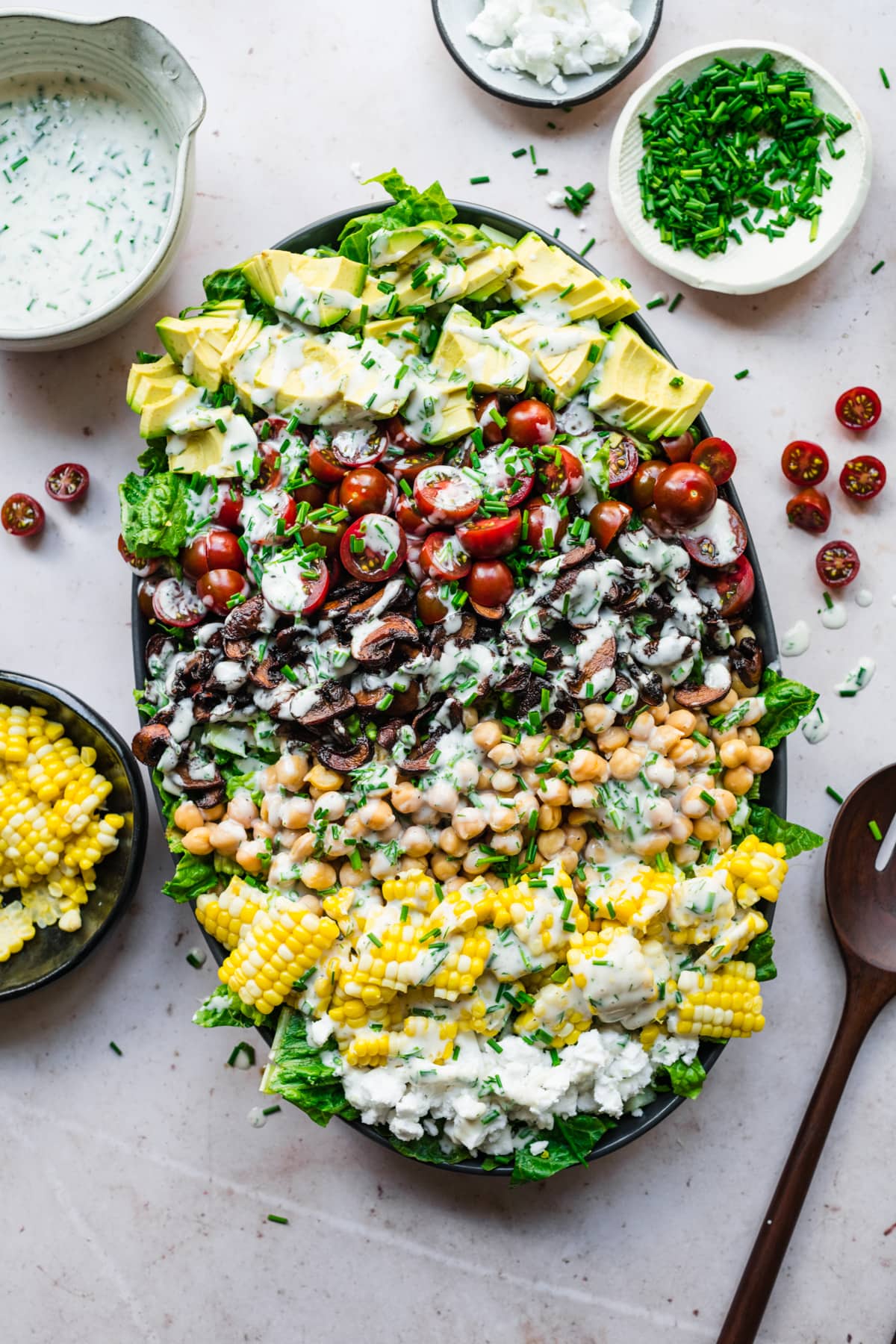 overhead view of vegan cobb salad on a platter topped with vegan ranch dressing. 