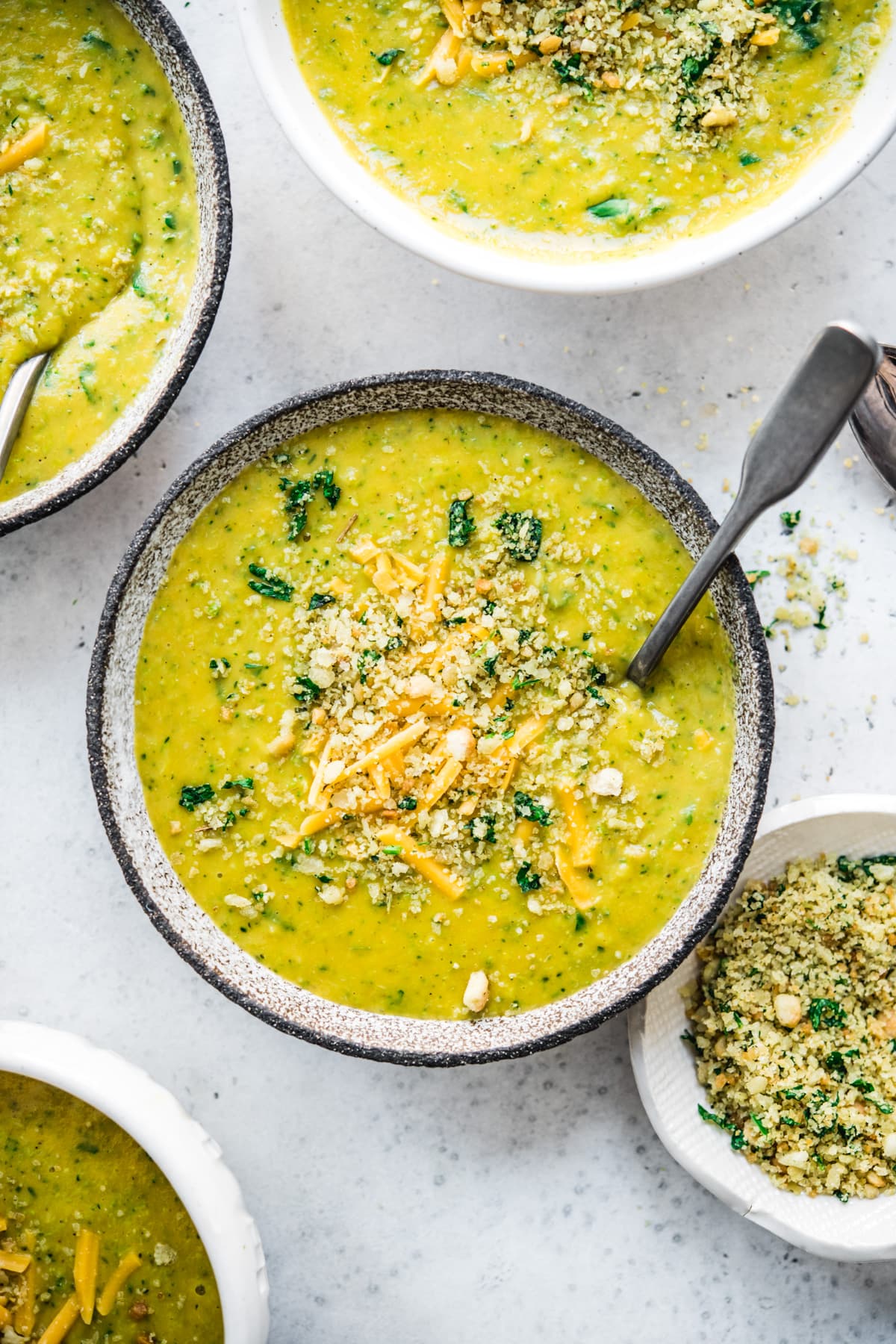 overhead view of vegan broccoli cheddar soup in a bowl with breadcrumb topping.