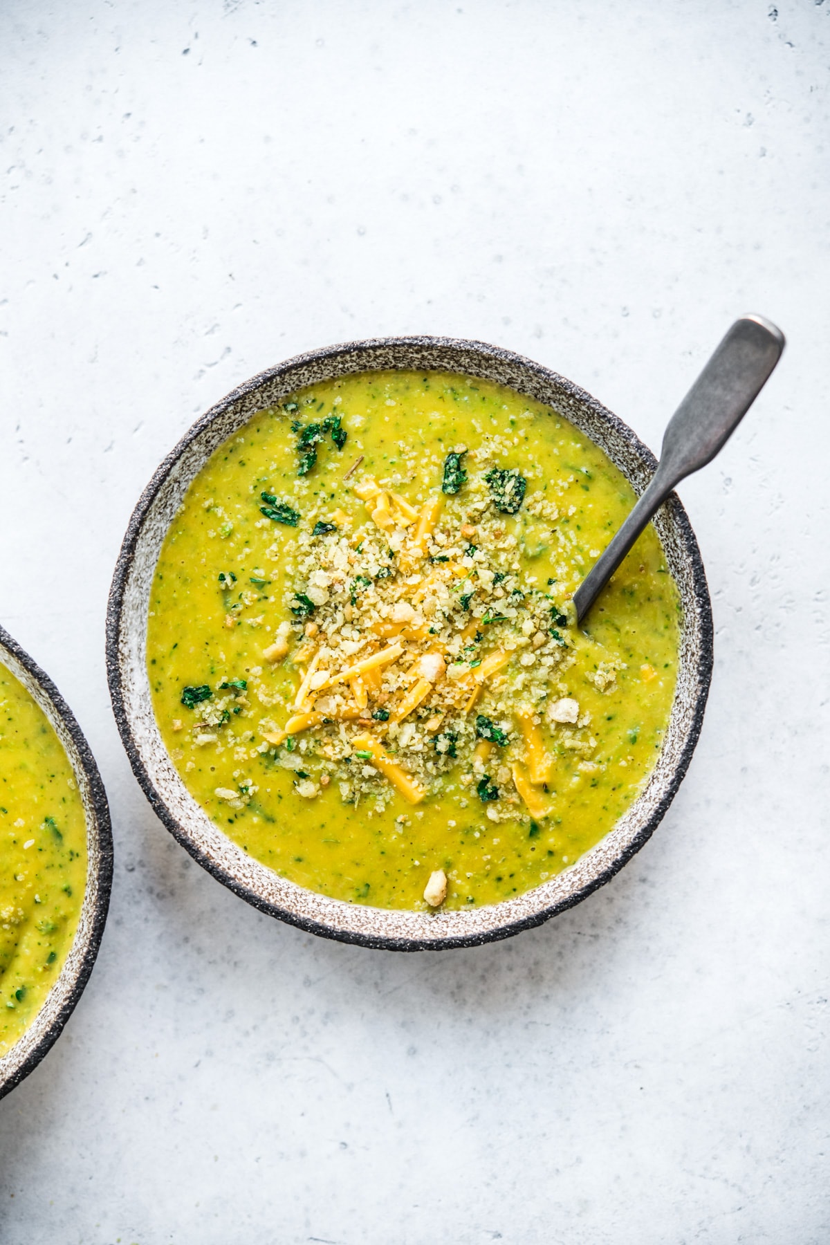 overhead view of vegan broccoli cheddar soup in a bowl with breadcrumb topping. 