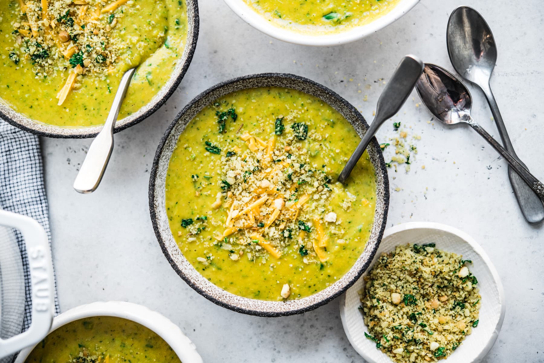 overhead view of vegan broccoli cheddar soup in a bowl with breadcrumb topping. 