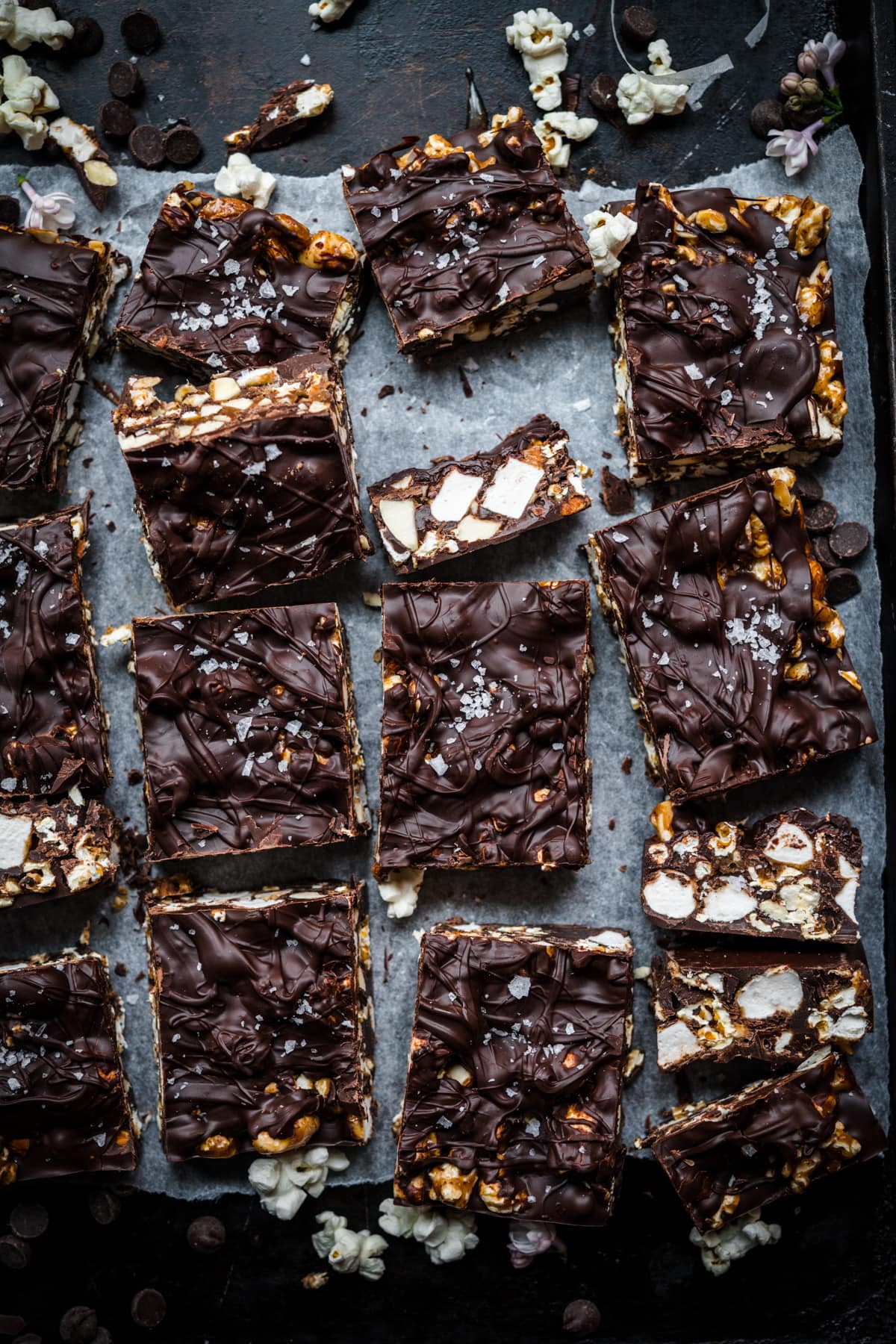 overhead view of salted caramel popcorn chocolate bars sliced into squares on parchment paper. 