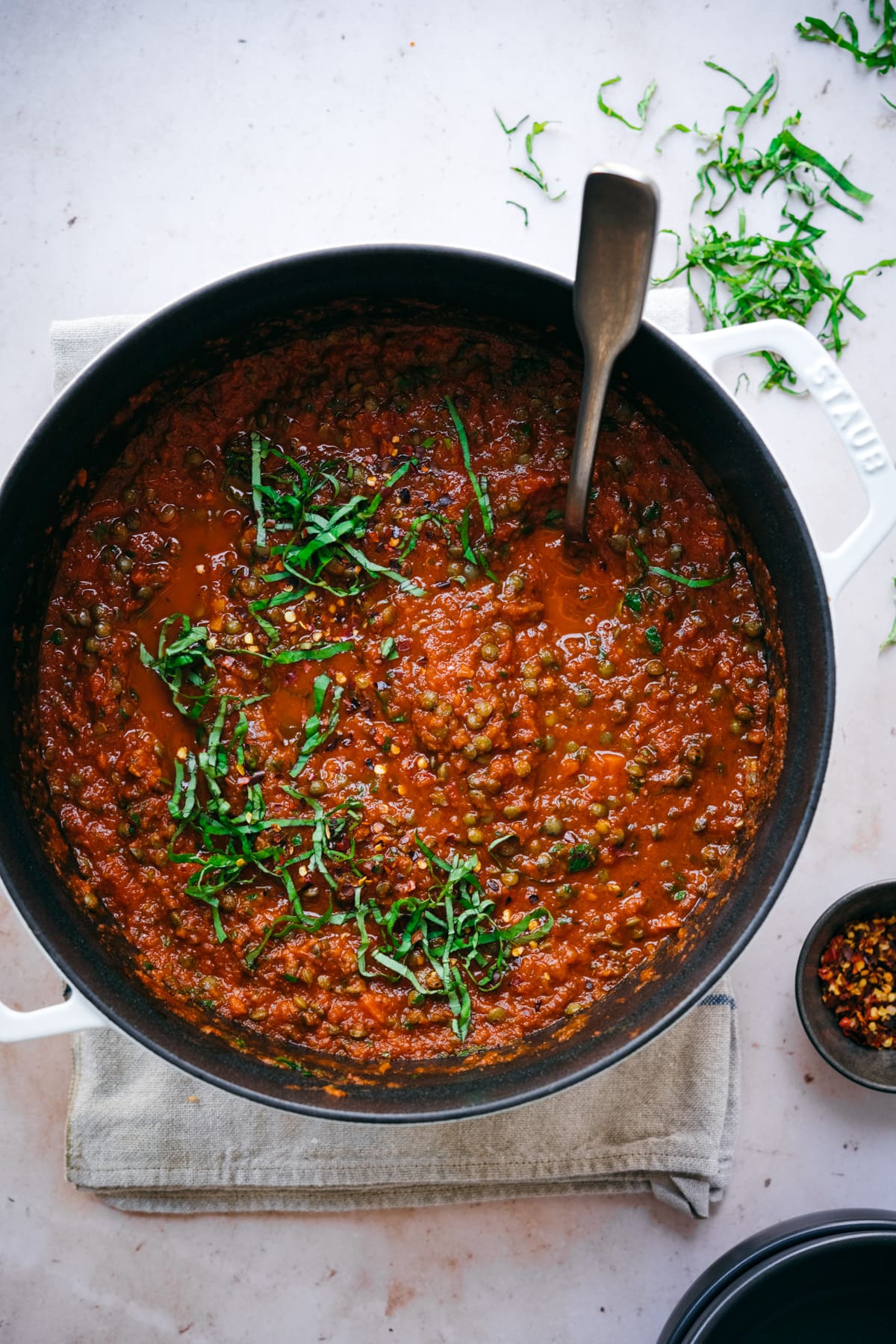 overhead view of vegan lentil bolognese sauce in large pot topped with fresh basil. 