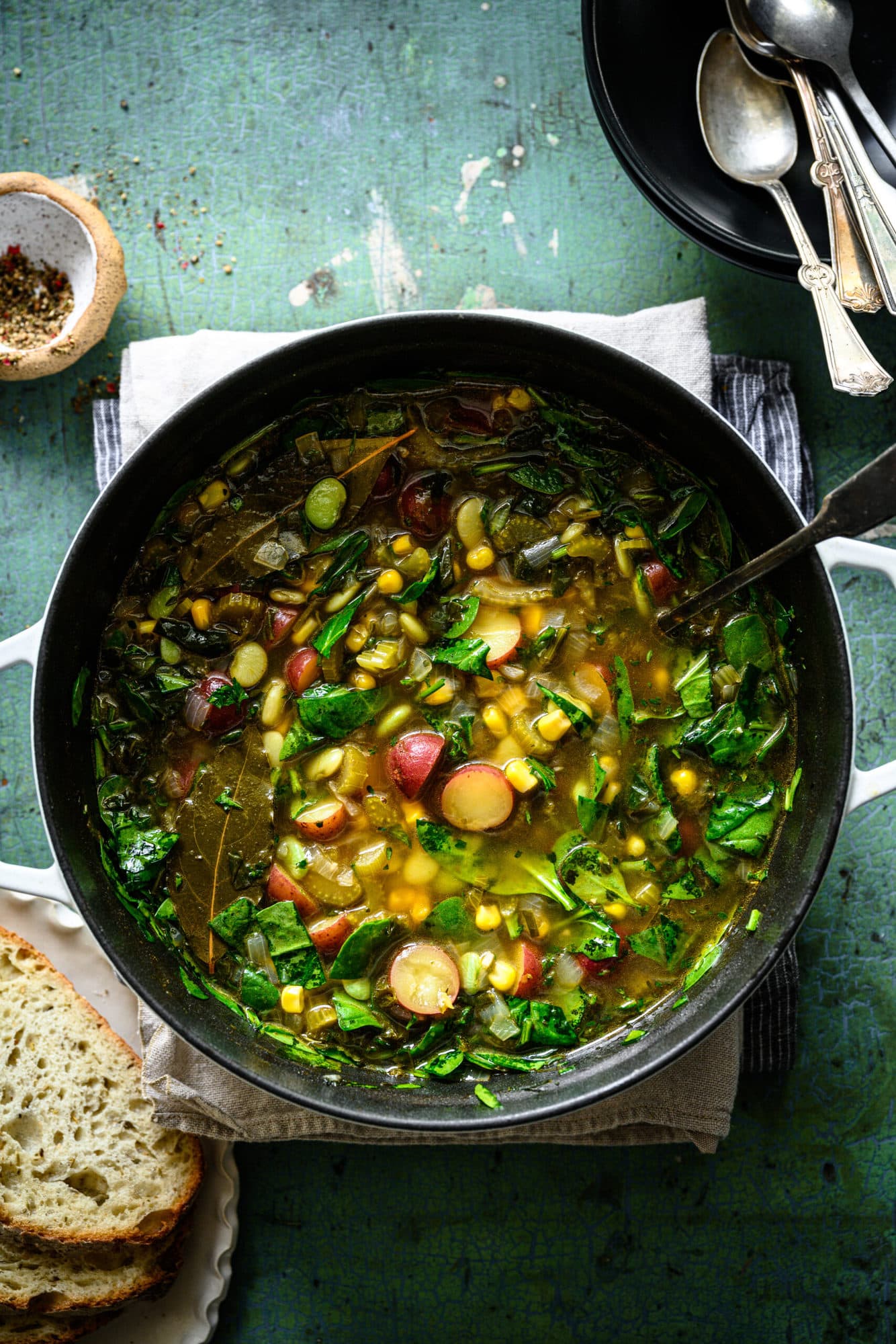 overhead view of vegan lima bean soup with potatoes and corn in a large pot. 