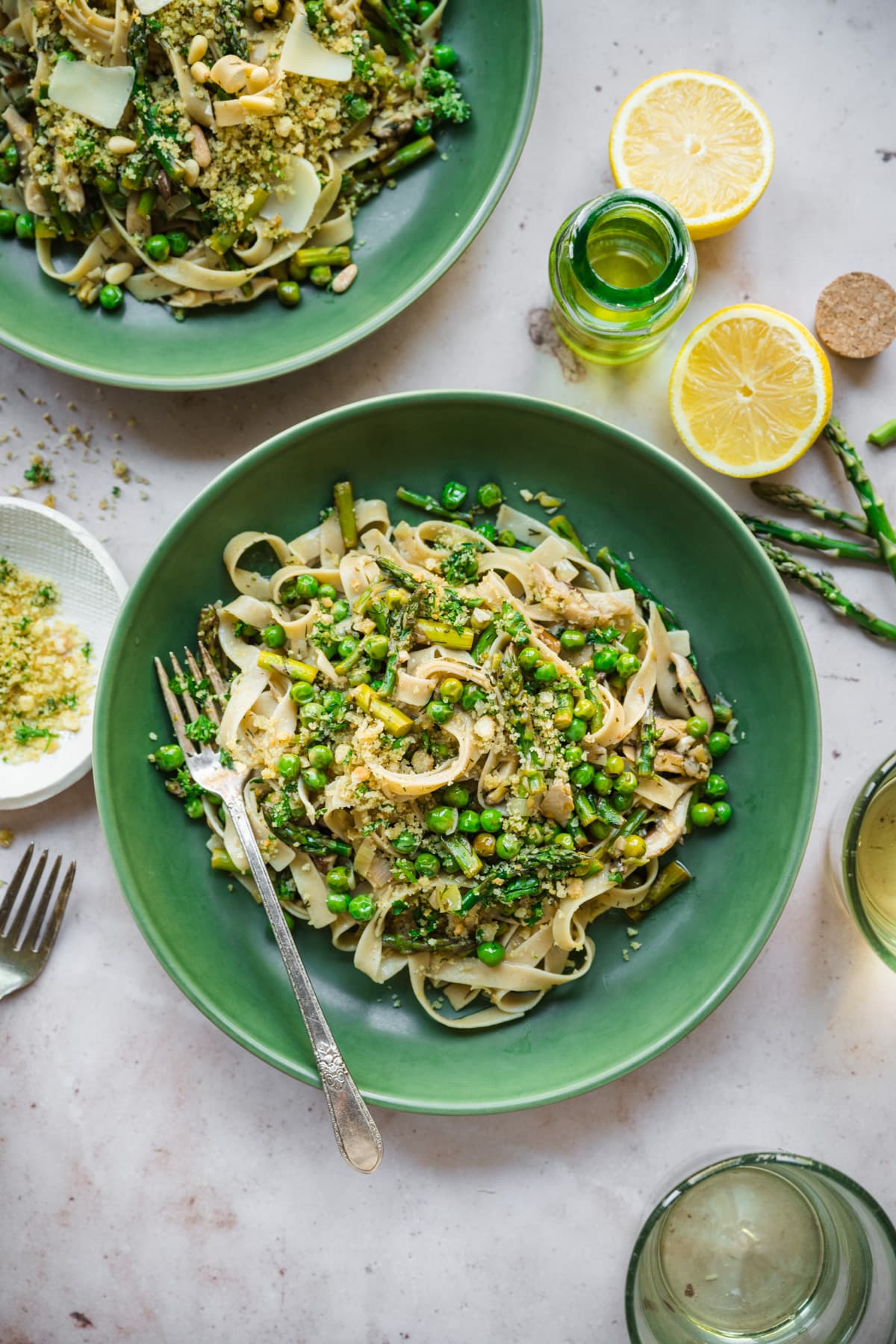 overhead view of vegan spring vegetable pasta plated in a green bowl with breadcrumb topping. 