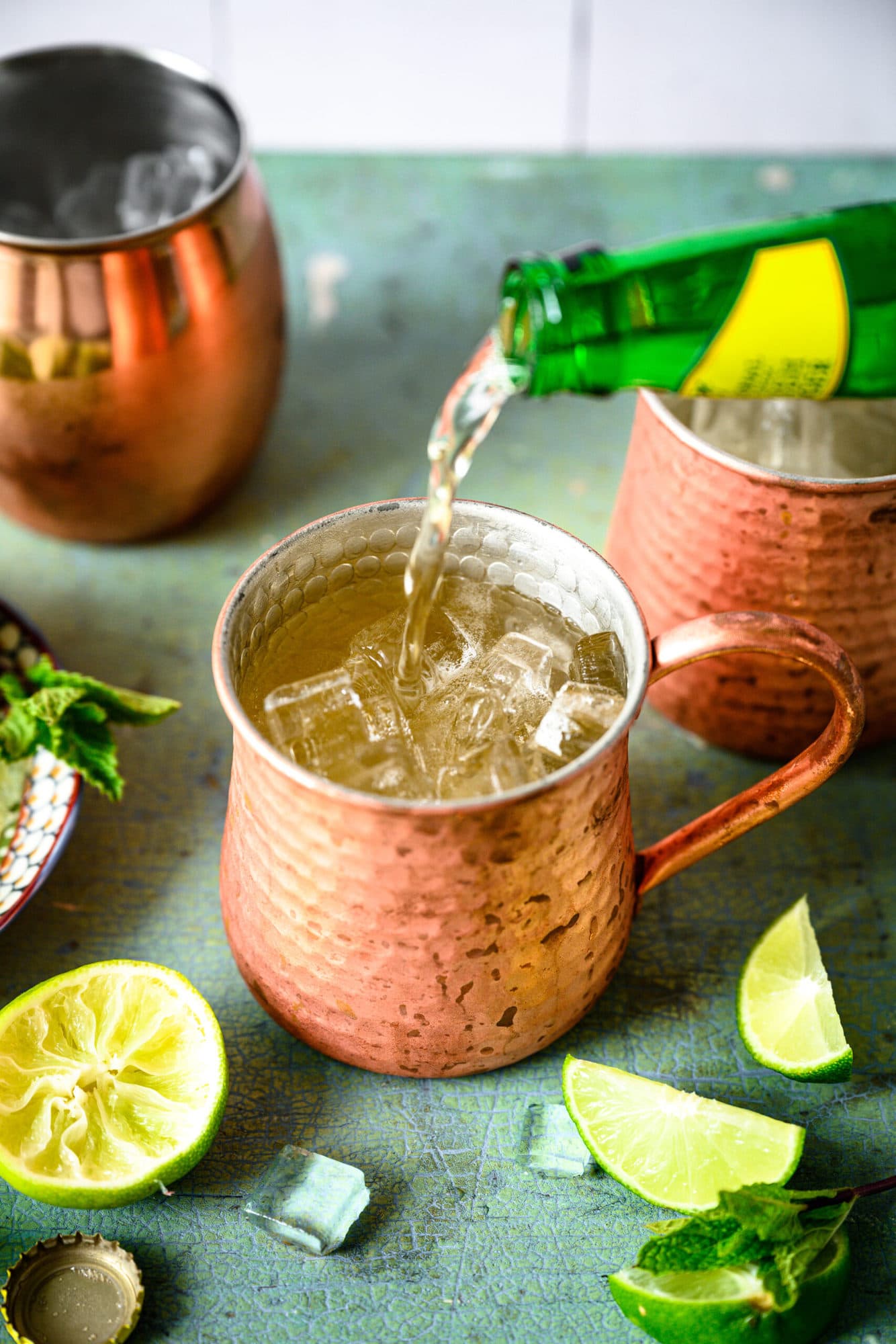 pouring ginger beer into tequila mule cocktail in copper mug. 