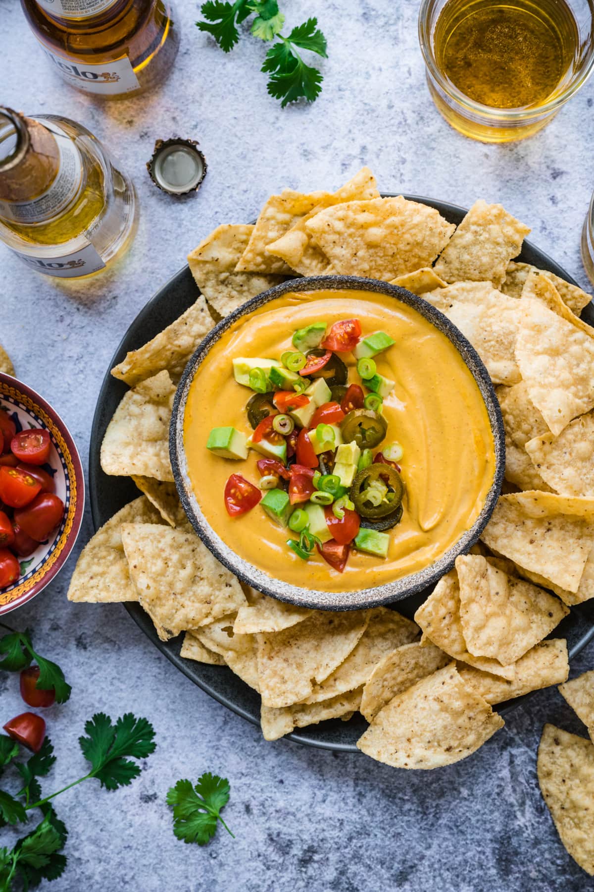 overhead view of vegan queso dip in a bowl with tortilla chips around it. 