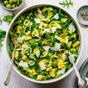 close up overhead view of corn avocado arugula salad with basil dressing in large bowl.