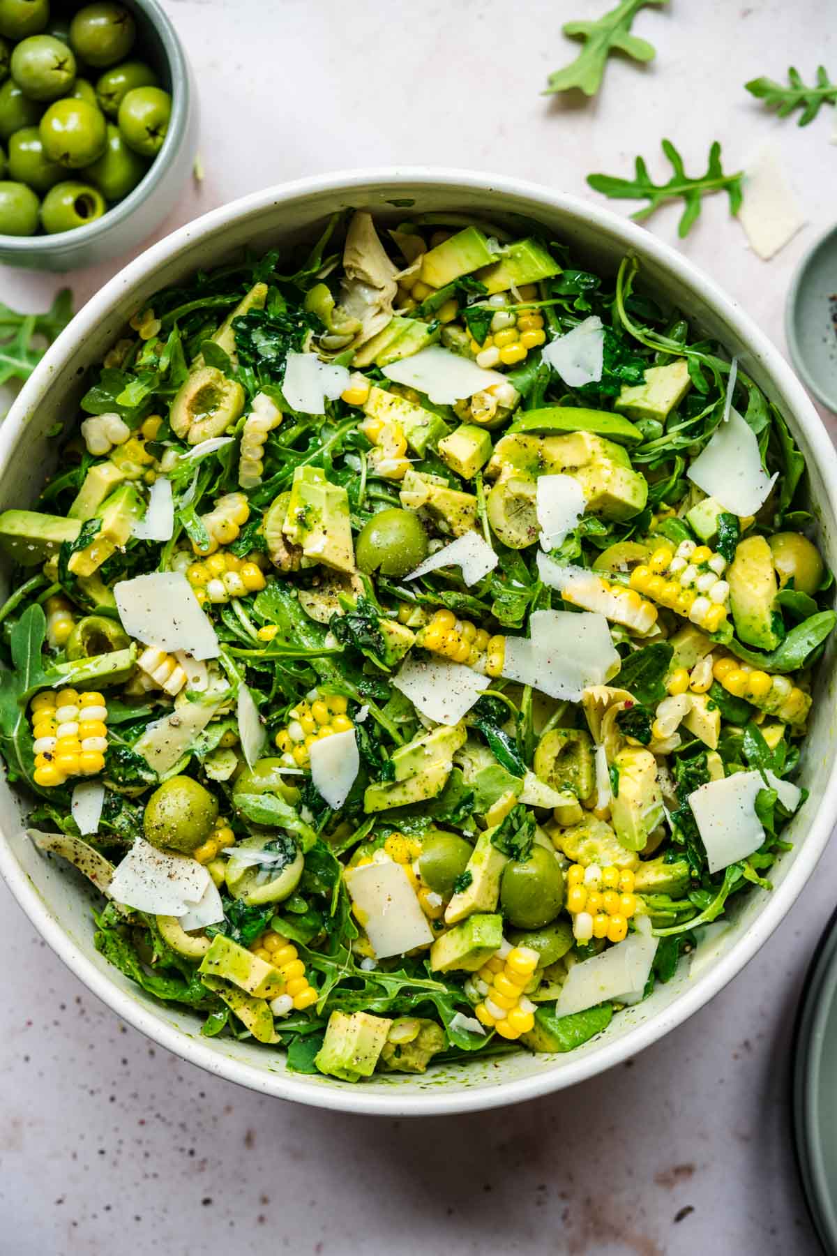 close up overhead view of corn avocado arugula salad with basil dressing in large bowl. 