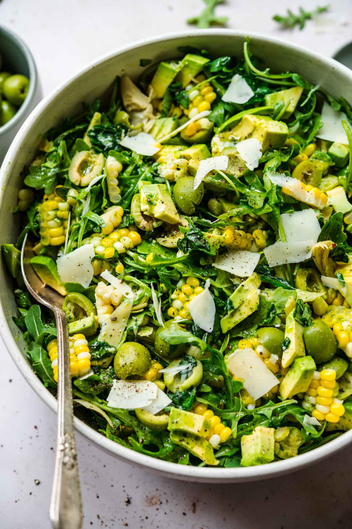 close up overhead view of corn avocado arugula salad with basil dressing in large bowl. 