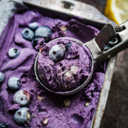 close up view of vegan lemon blueberry ice cream in a loaf pan ice cream in scoop.