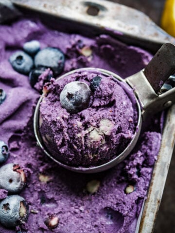 close up view of vegan lemon blueberry ice cream in a loaf pan ice cream in scoop.