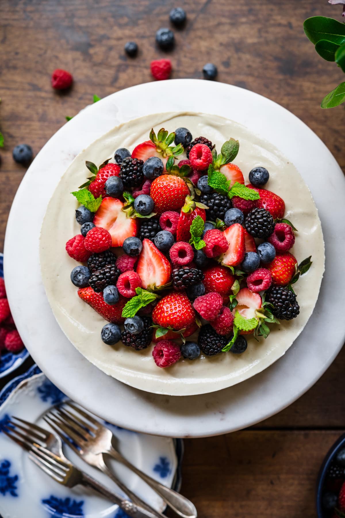 overhead view of no bake vegan cheesecake on cake stand topped with fresh berries. 