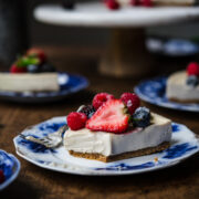close up side view of slice of vegan no bake cheesecake on a blue china plate with fresh berries.