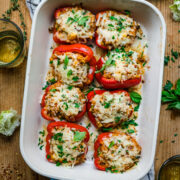 overhead view of vegan stuffed red peppers with cheese on top in baking dish.