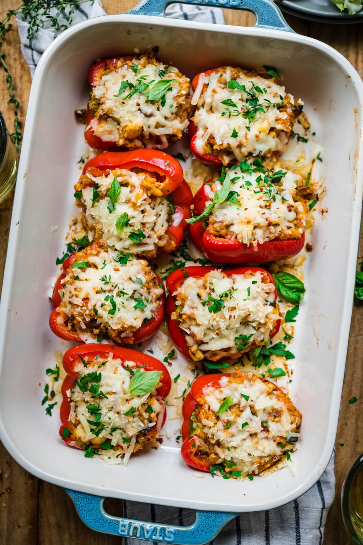 overhead view of vegan stuffed red peppers with cheese on top in baking dish. 