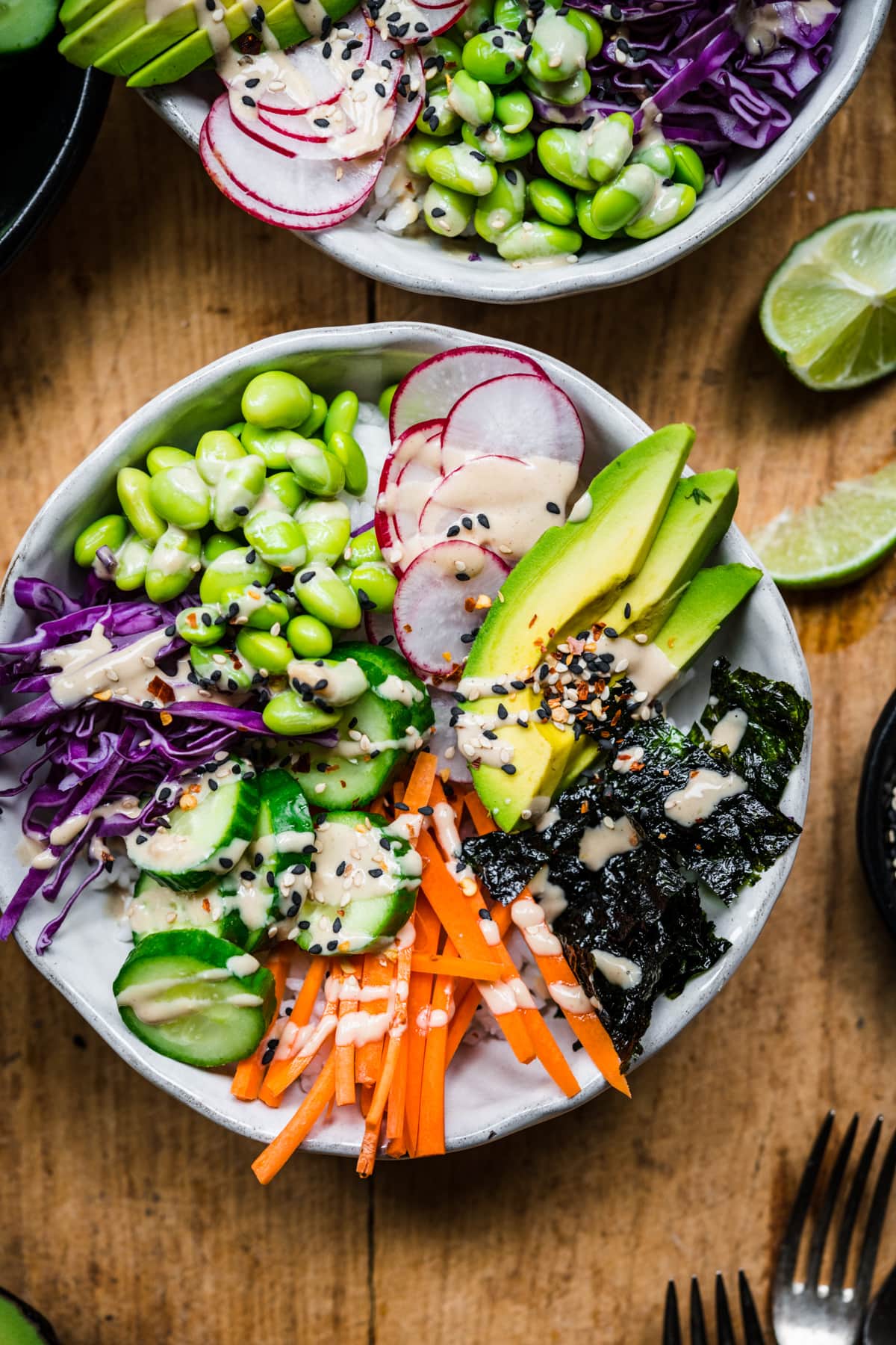 overhead view of vegan sushi bowl with avocado, radishes, cucumber, edamame and miso tahini dressing. 