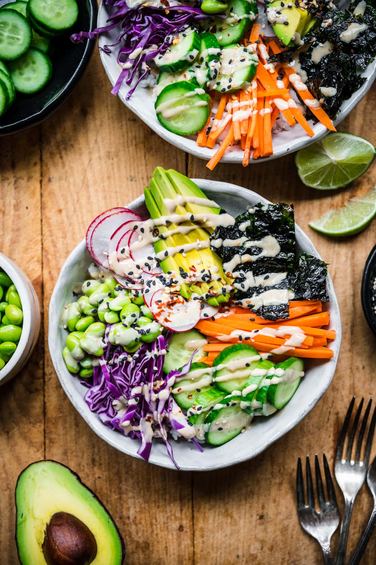 overhead view of vegan sushi bowl with avocado, radishes, cucumber, edamame and miso tahini dressing.