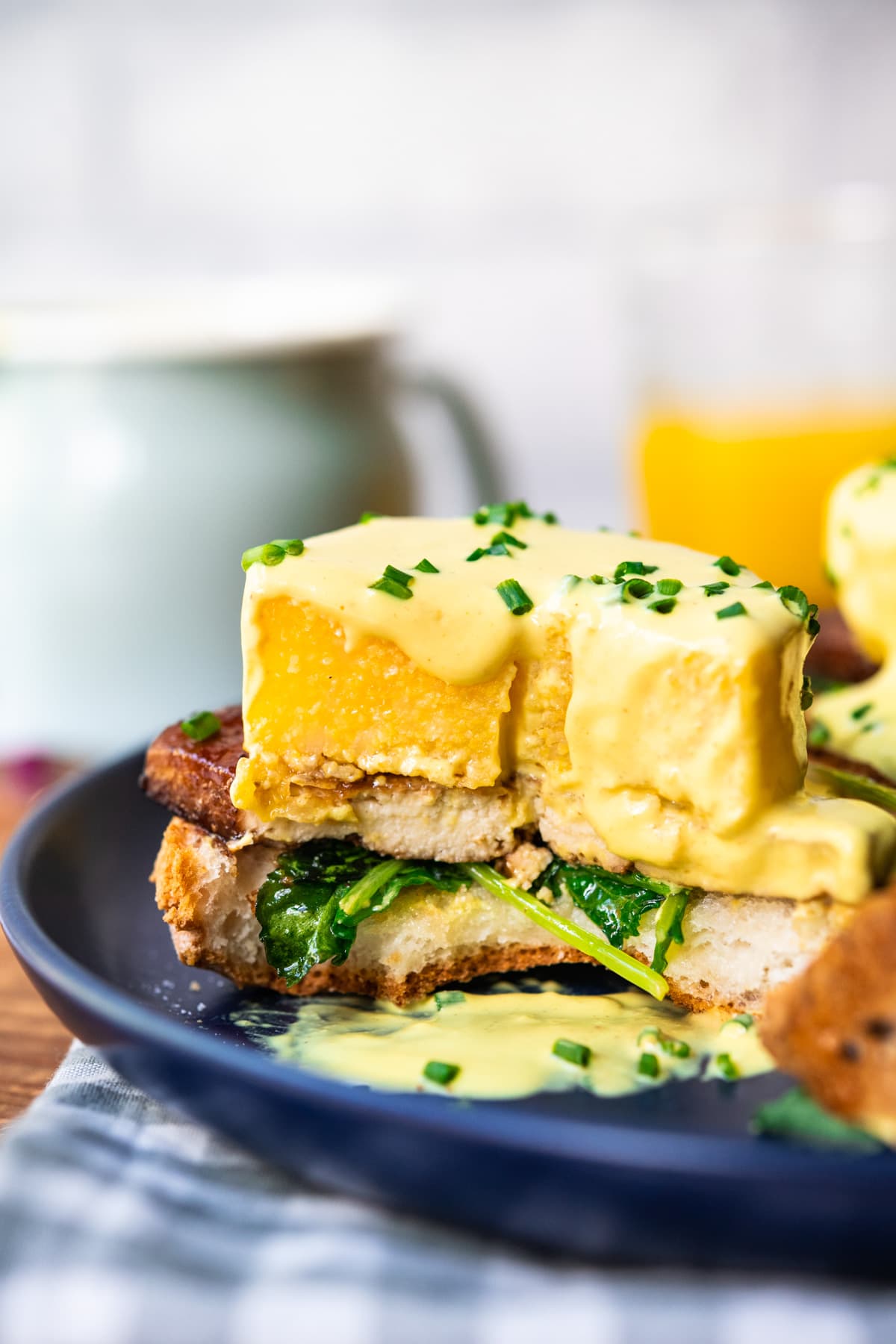 close up side view of cross section of polenta eggs benedict with vegan hollandaise sauce. 