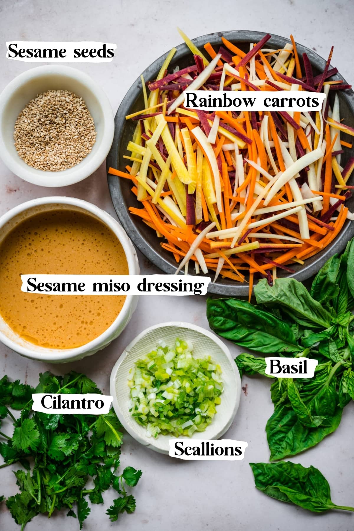 overhead view of ingredients for carrot sesame salad on surface with text labels. 