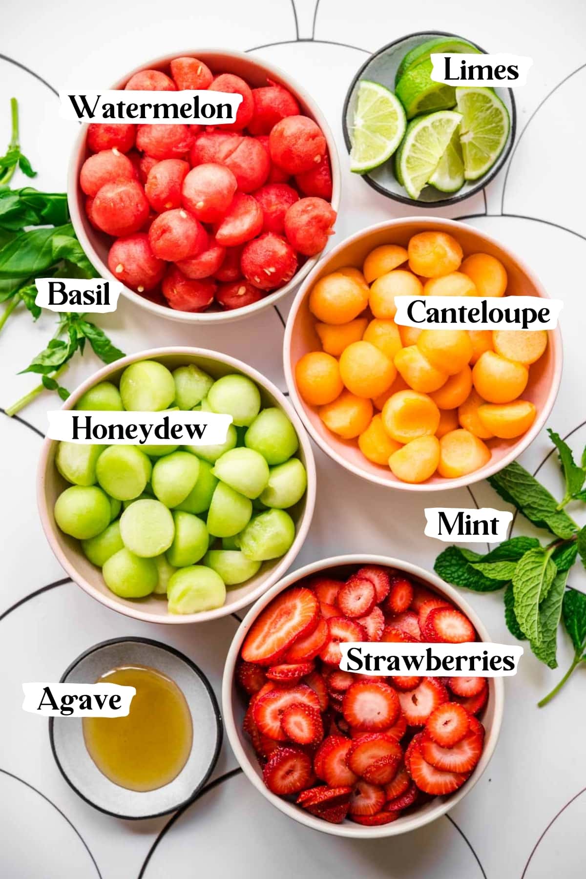 overhead view of ingredients for melon ball salad in bowls. 