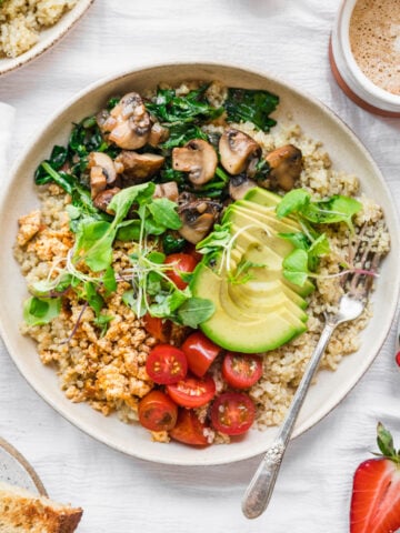 overhead view of vegan savory quinoa breakfast bowl with tofu, avocado and mushrooms.
