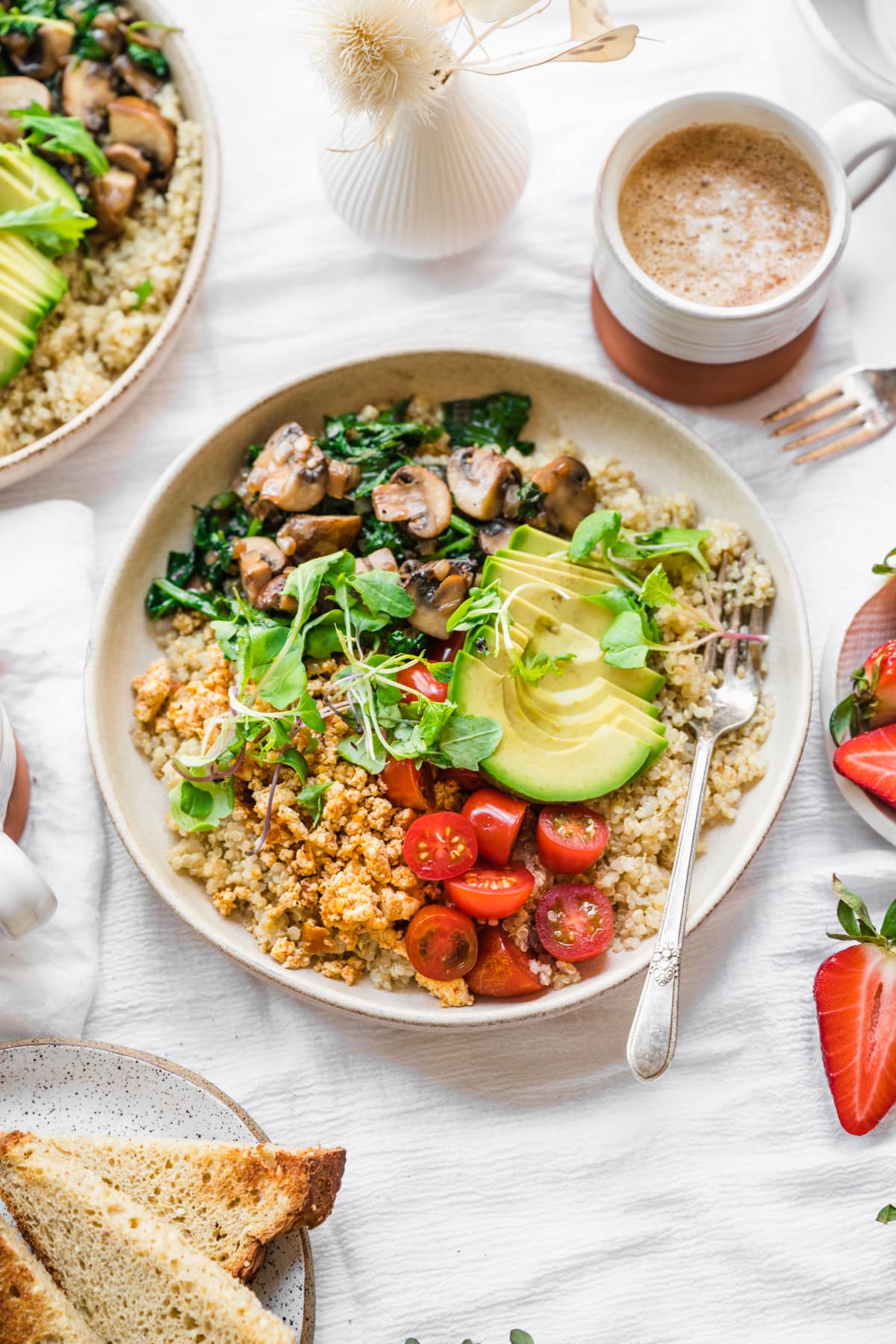 overhead view of vegan savory quinoa breakfast bowl with tofu, avocado and mushrooms. 